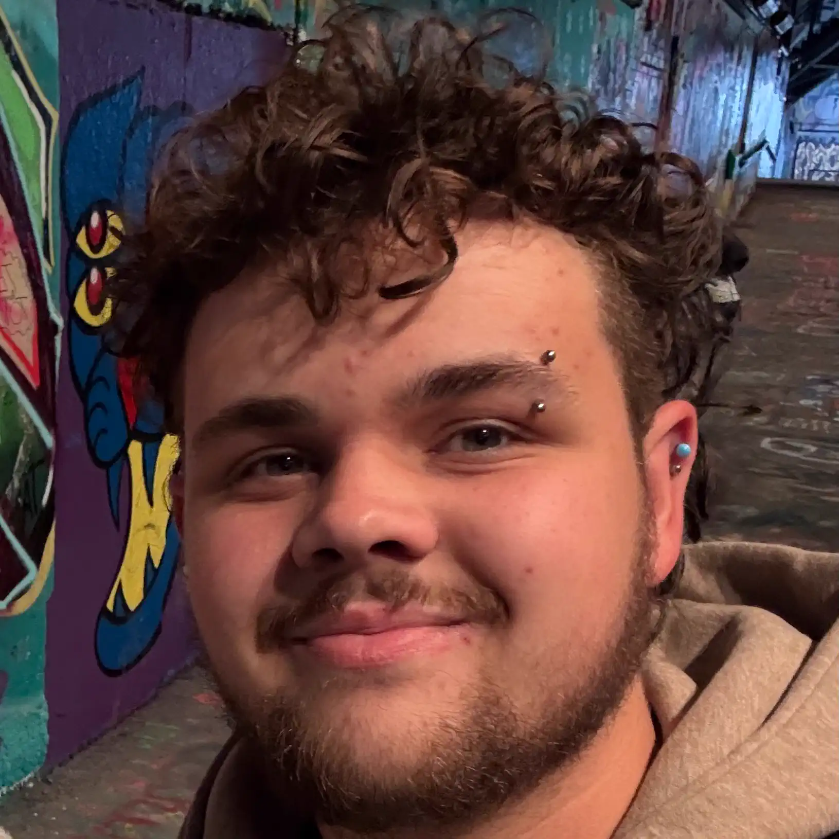 Harrison Birdsey smiling at the camera with graffiti in the background